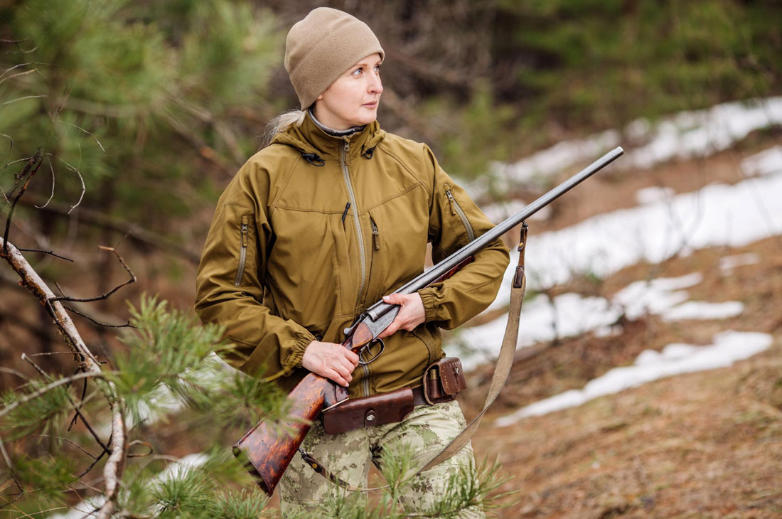 Mujer en el monte sujetando una escopeta